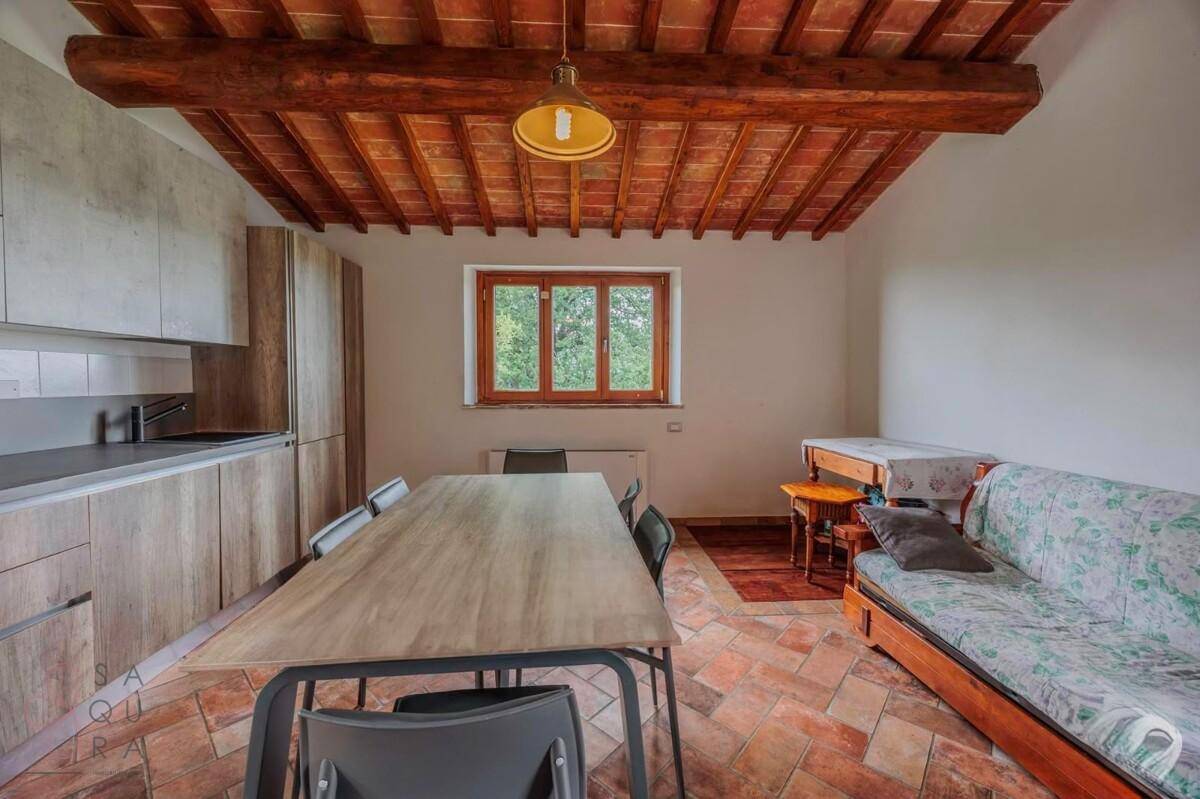 Moderne Küche mit Essbereich, Terrakottaboden und rustikaler Holzbalkendecke.