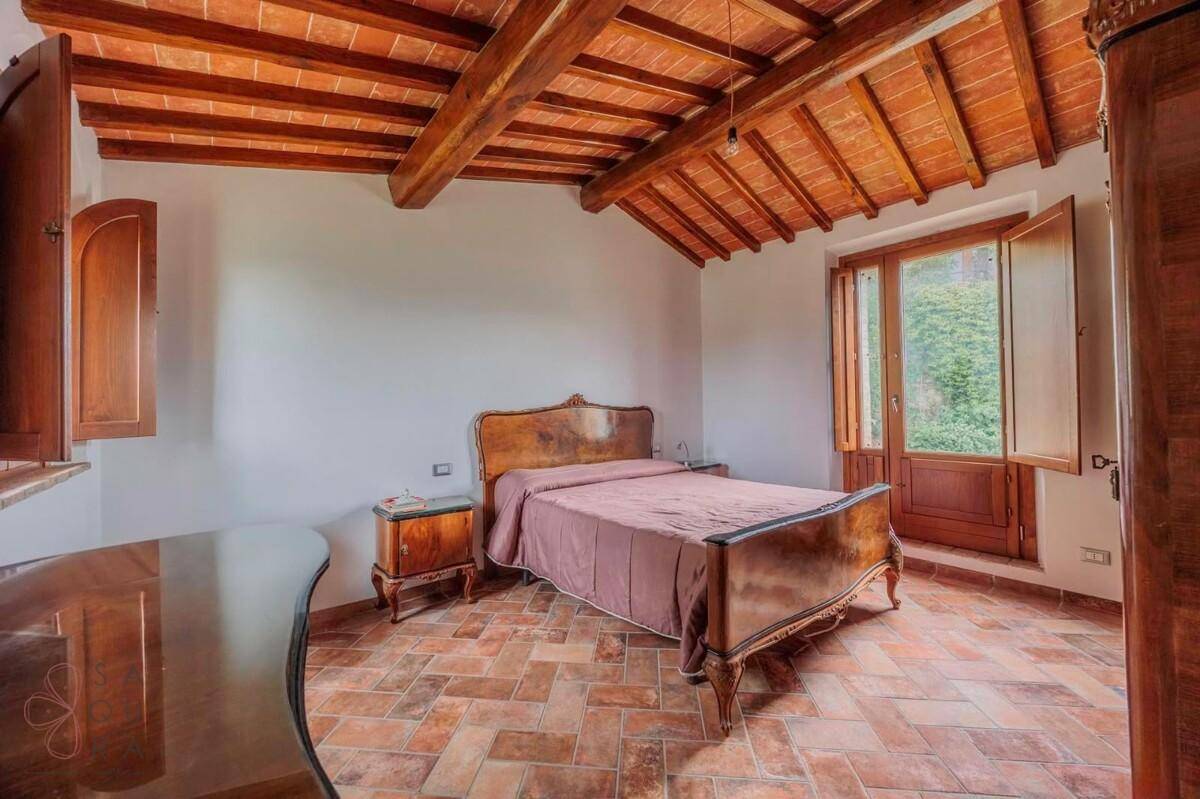 Gemütliches Schlafzimmer mit Terrakottaboden, Holzbalkendecke und traditionellen Möbeln.