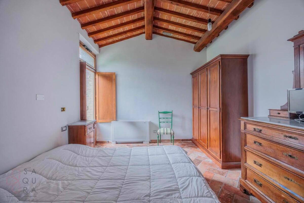 Helles Schlafzimmer mit Terrakottaboden, Holzbalkendecke und traditionellen Holzmöbeln.