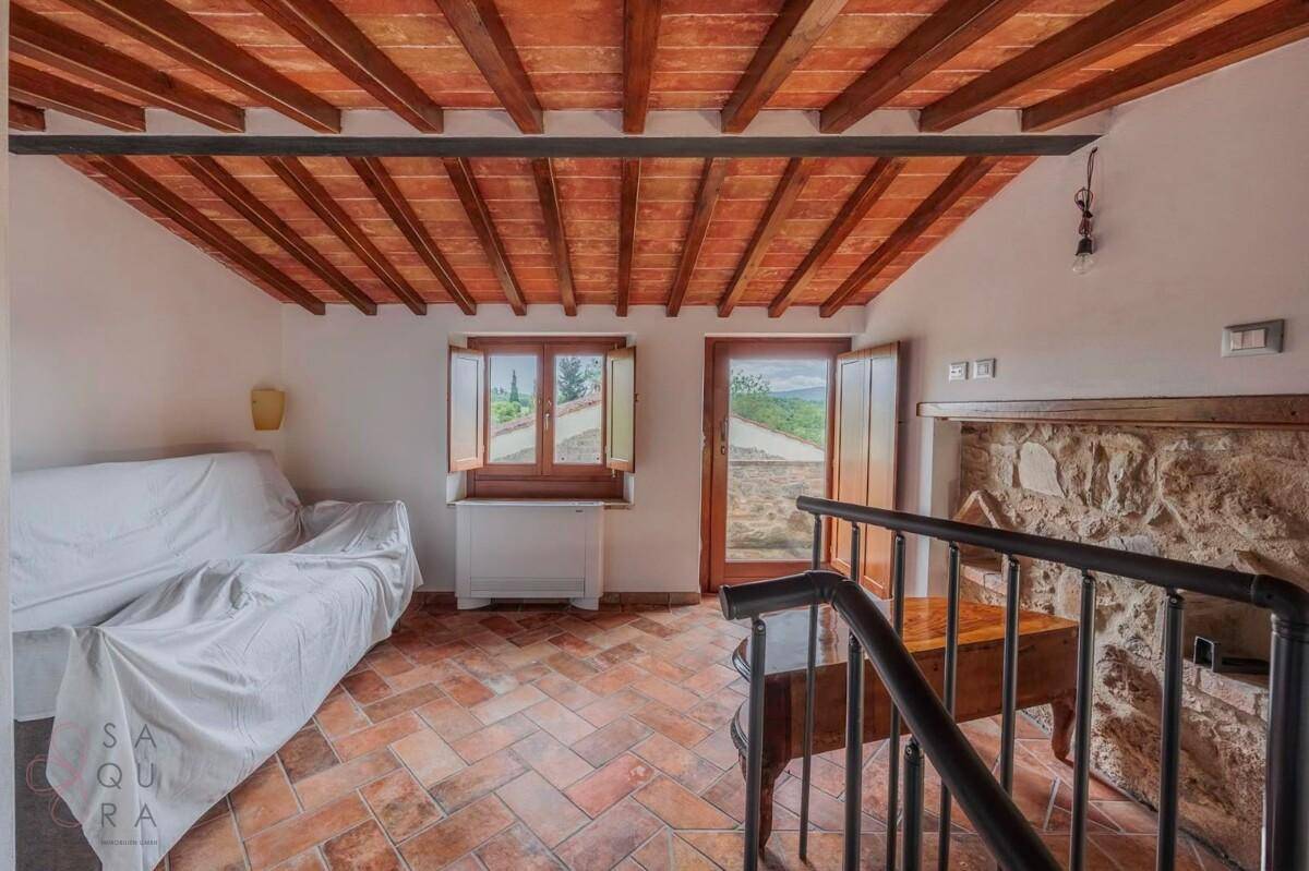 Wohnbereich mit Terrakottaboden, sichtbaren Holzbalken und einer dekorativen Steinwand.