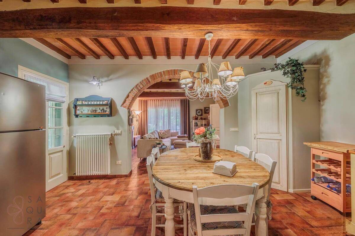 Rustikaler Essbereich mit Holztisch, Kronleuchter und Blick in das angrenzende Wohnzimmer.