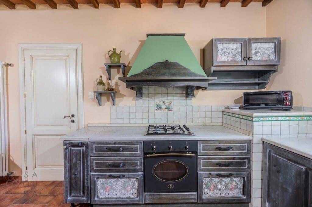 Detailansicht der traditionellen Küche mit Gasherd, Backofen und gefliestem Spritzschutz.