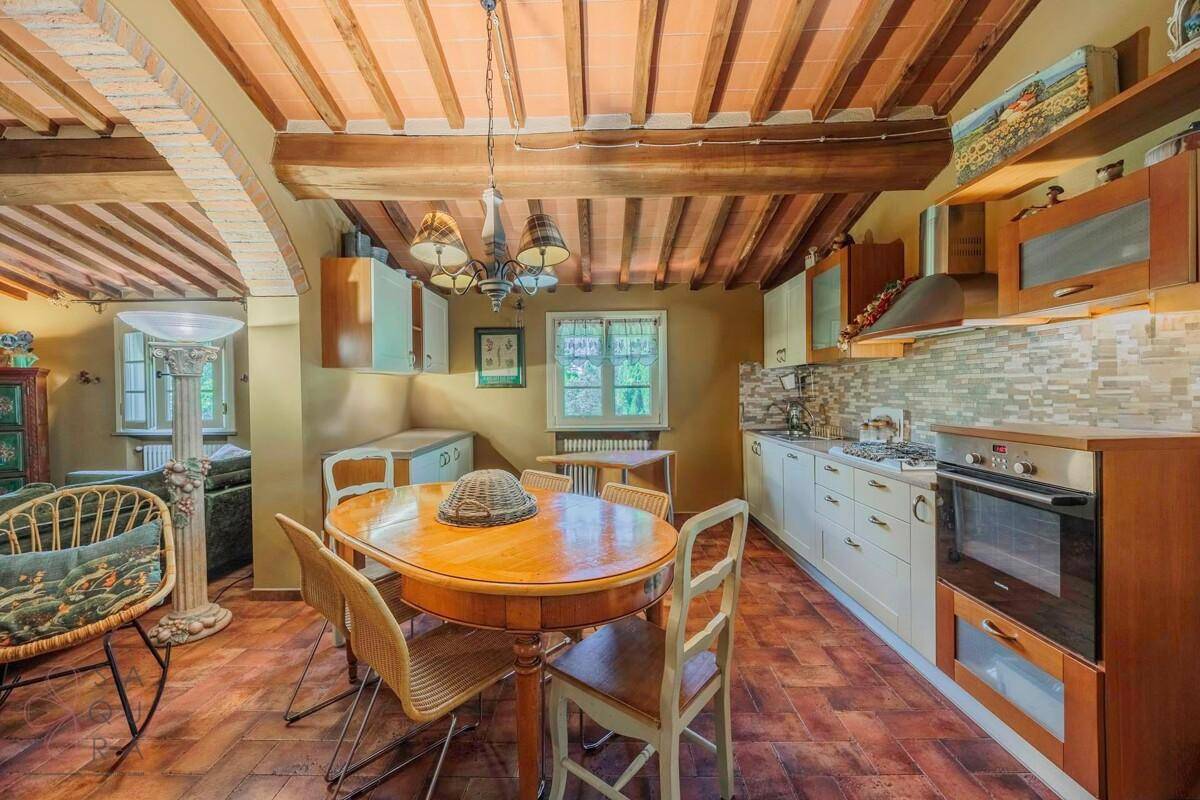 Gemütliche Wohnküche mit Holzbalkendecke, Essbereich und traditionellen Küchenschränken.