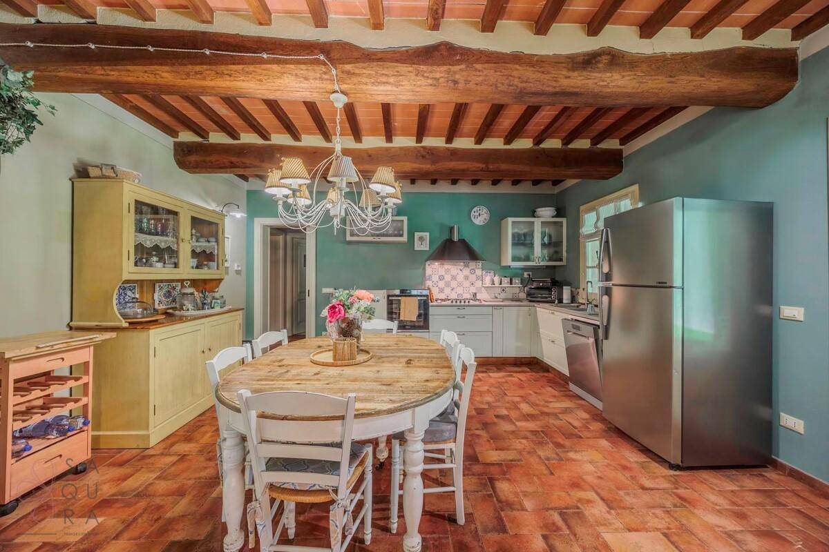 Geräumige Wohnküche mit Essbereich, modernen Geräten und Holzbalkendecke.