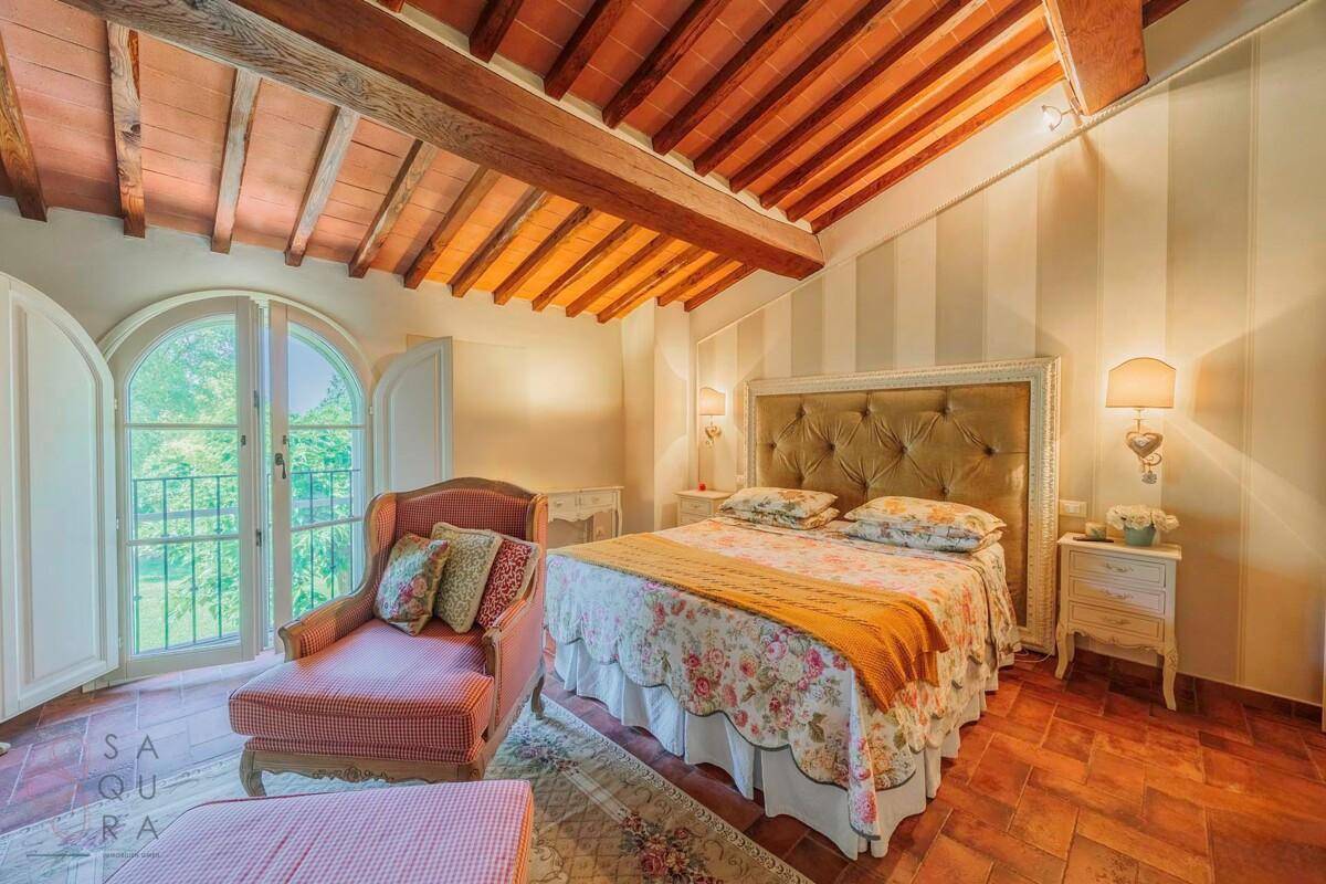 Elegantes Schlafzimmer mit gepolstertem Kopfteil, floraler Bettwäsche und französischem Balkon.