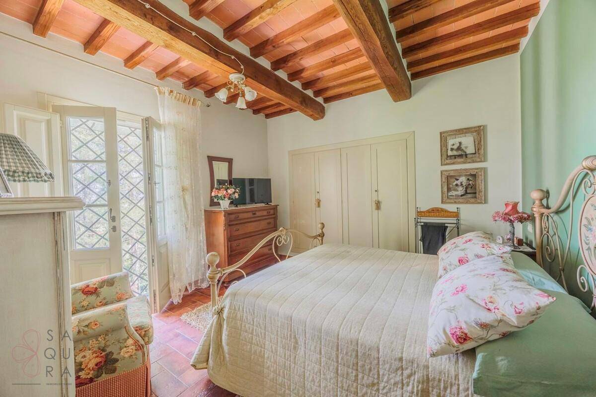 Helles Schlafzimmer mit schmiedeeisernem Bett, Kleiderschrank und Zugang zum Außenbereich.
