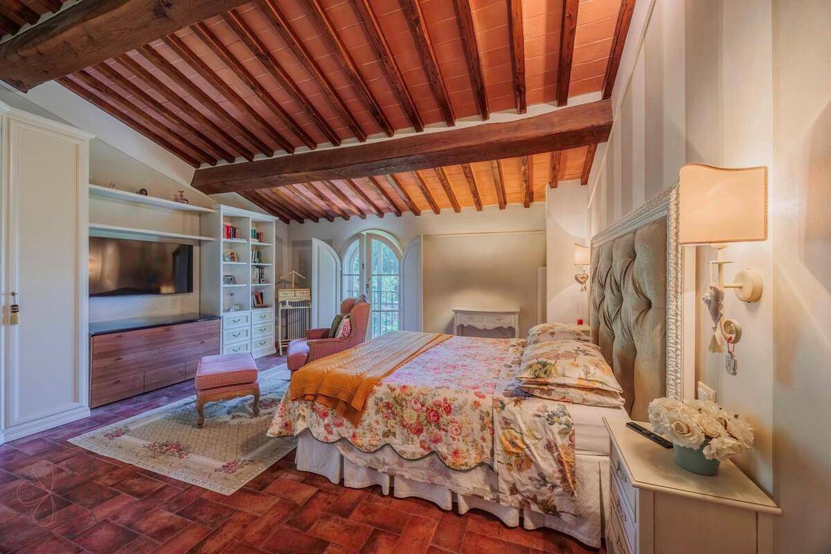 Geräumiges Schlafzimmer mit Doppelbett, integriertem Bücherregal und Holzbalkendecke.