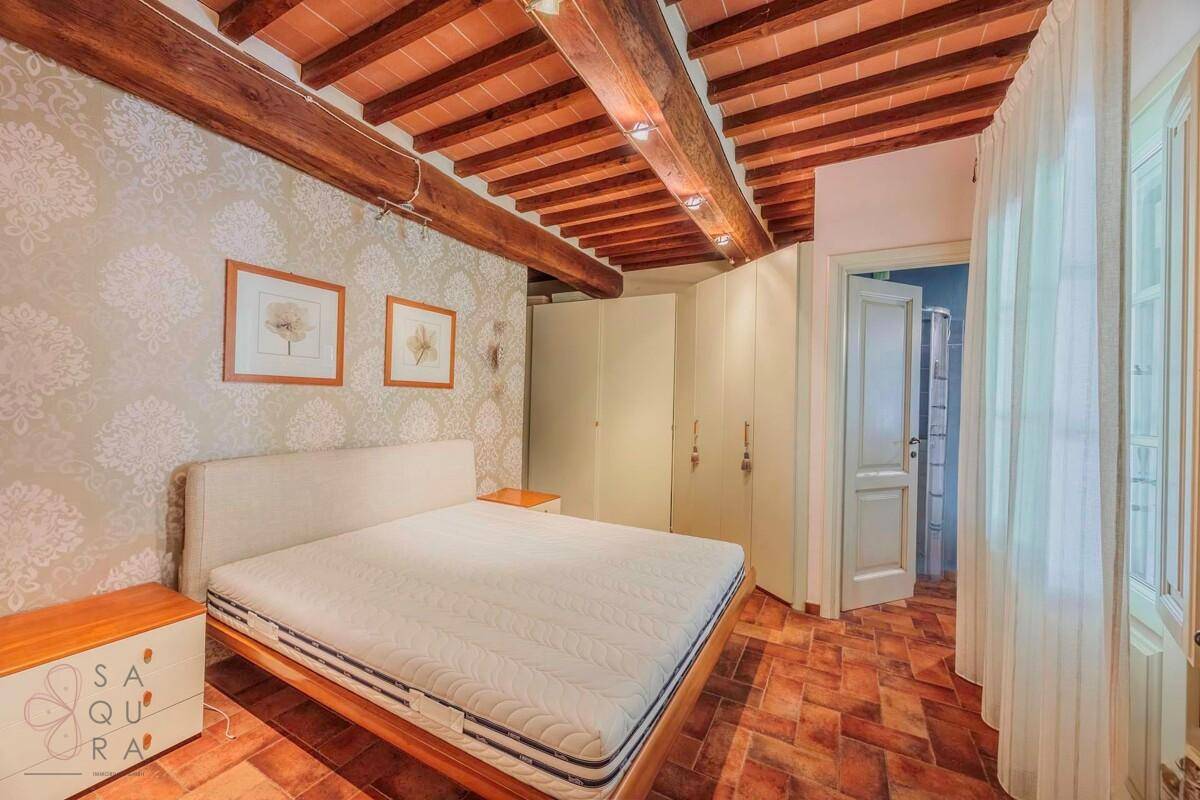 Schlafzimmer mit Doppelbett, Einbauschränken und rustikaler Holzbalkendecke.