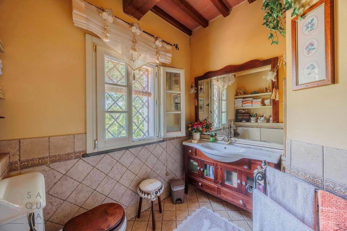 Traditionelles Badezimmer mit Holzwaschtisch, Spiegel und Fenster.
