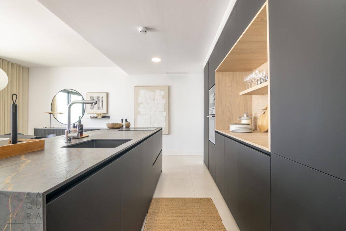 Elegante, moderne Küche mit schwarzer Kücheninsel, integriertem Spülbecken und Holzdetails.
