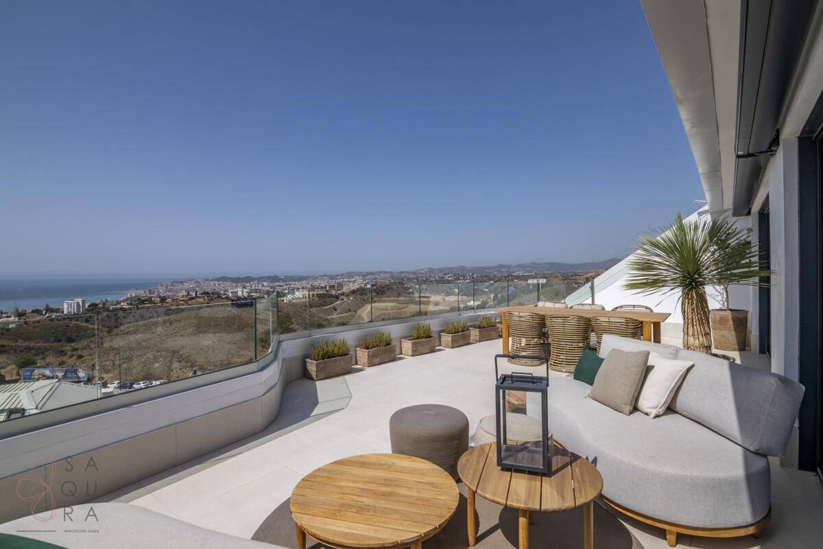 Große Sonnenterrasse mit bequemen Lounge-Möbeln und Panoramablick auf das Meer und die Küste.