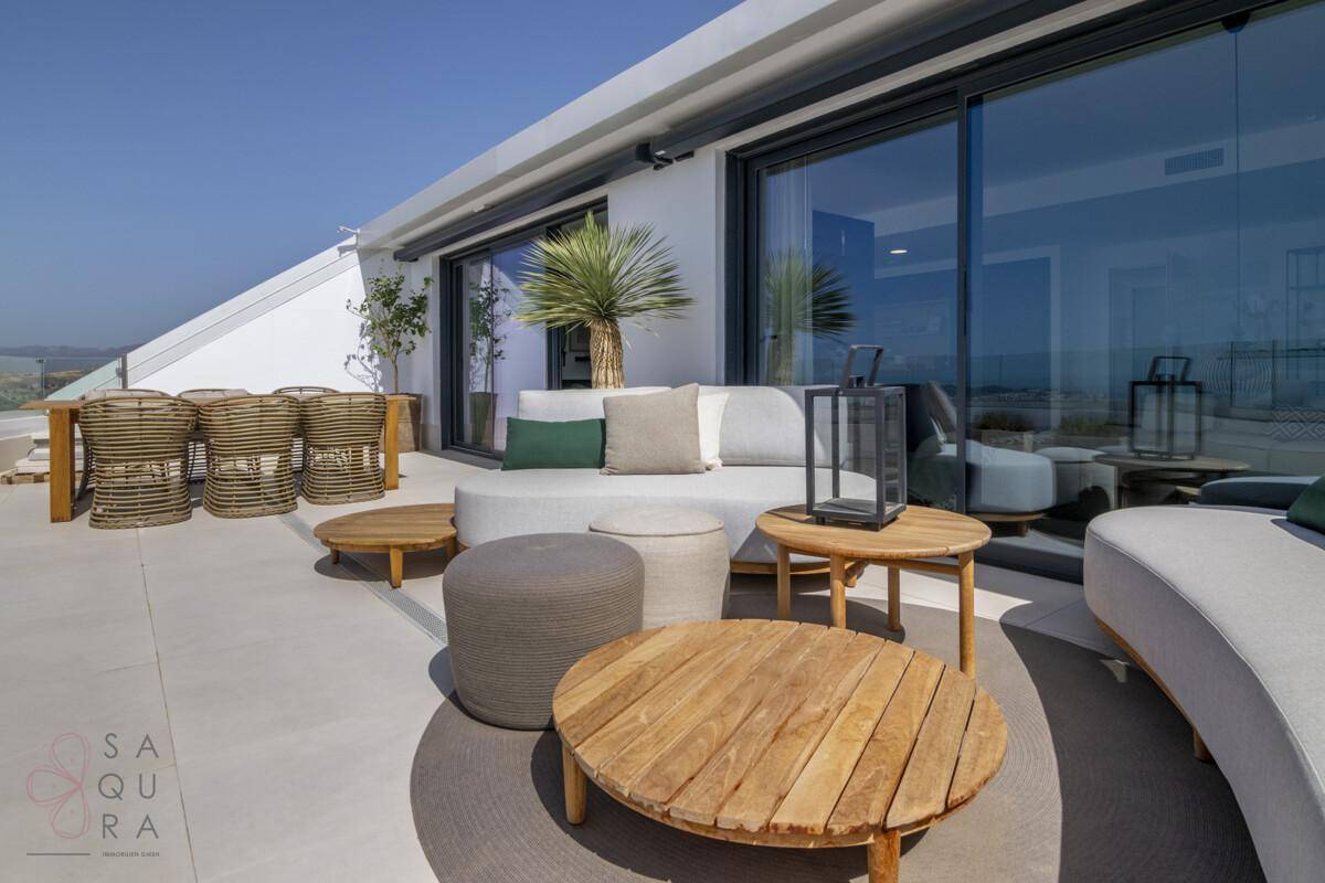 Stilvolle Dachterrasse mit modernen Lounge-Möbeln, Holztischen und einer Palme unter blauem Himmel.