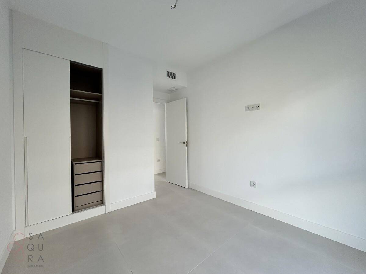 Unmöbliertes Schlafzimmer mit integriertem Kleiderschrank und hellem Fliesenboden.
