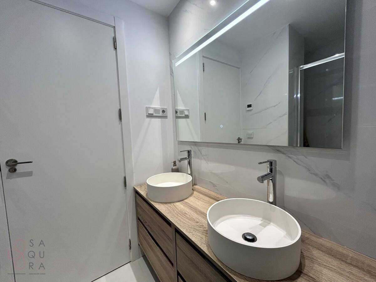 Modernes Badezimmer mit Doppelwaschbecken, großem Spiegel und Holzwaschtisch.