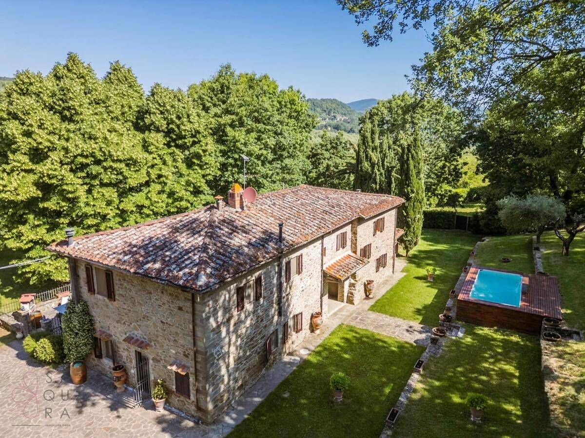 Luftaufnahme eines charmanten Landhauses mit Pool und weitläufigem Garten in ländlicher Umgebung.