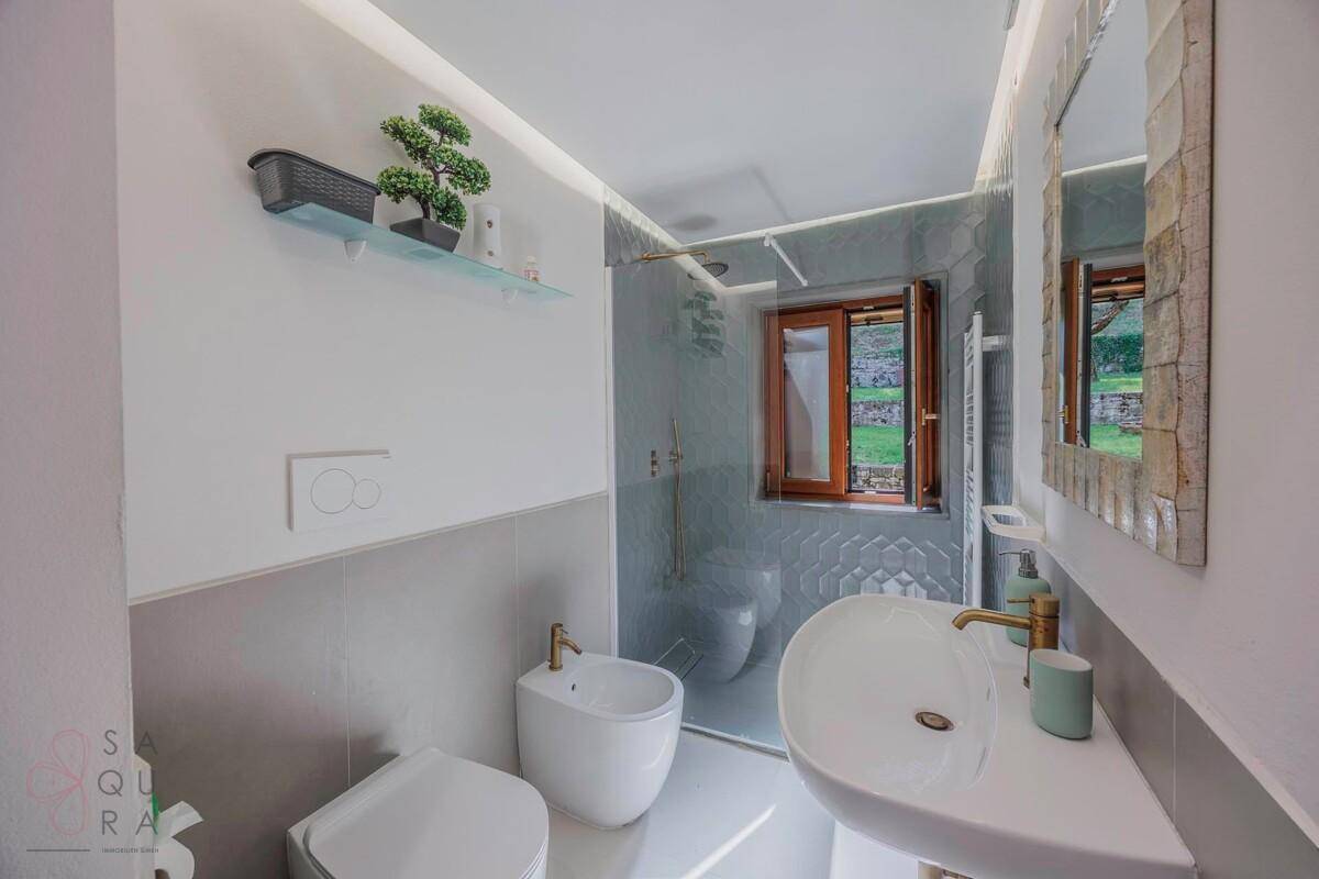 Modernes Badezimmer mit grauen Fliesen, begehbarer Dusche und Bidet.