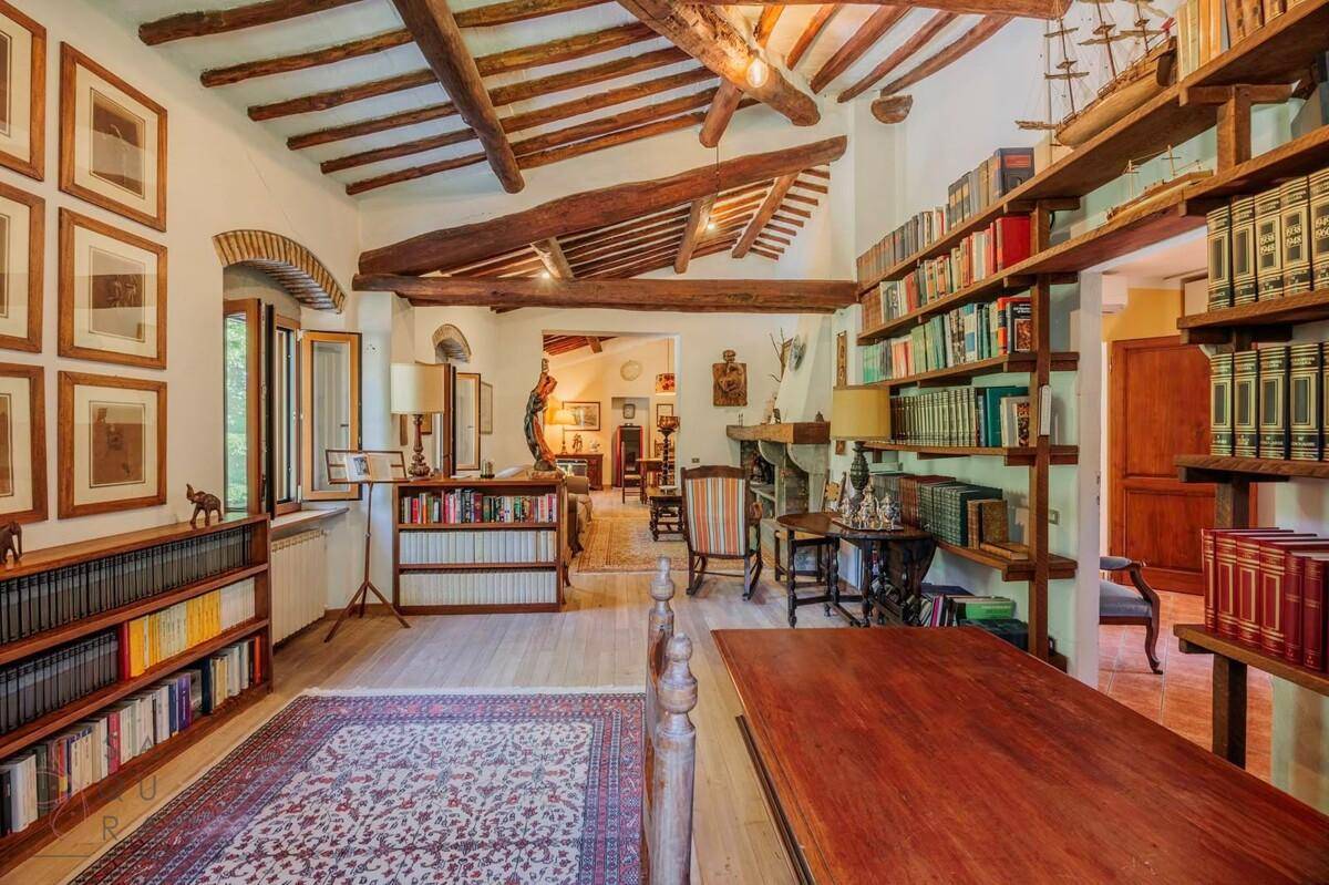 Elegante Bibliothek mit hohen Bücherregalen, Holzbalkendecke und traditioneller Einrichtung.