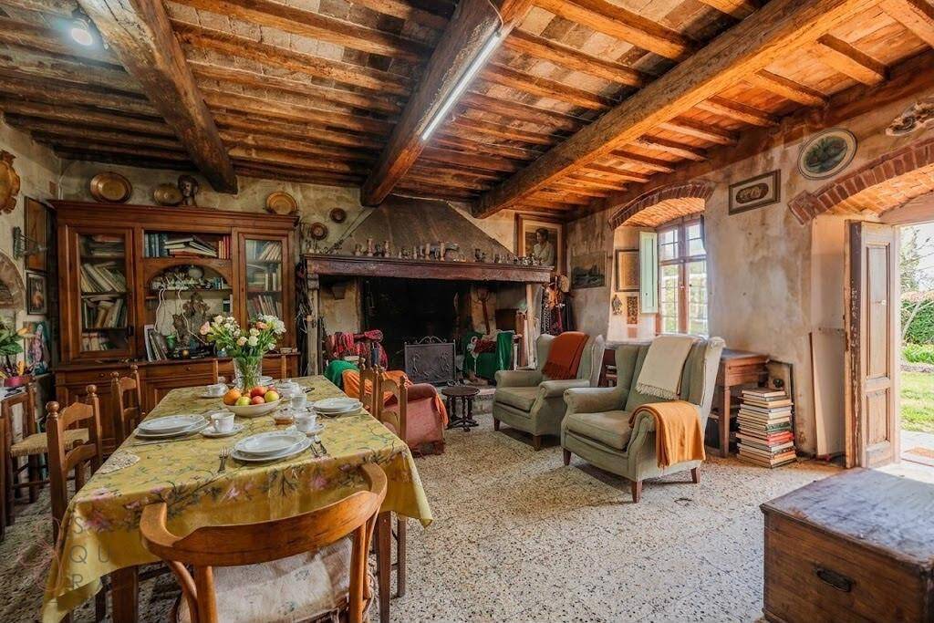 Gemütlicher Wohn- und Essbereich mit großem Kamin, Holzbalkendecke und rustikalen Möbeln.