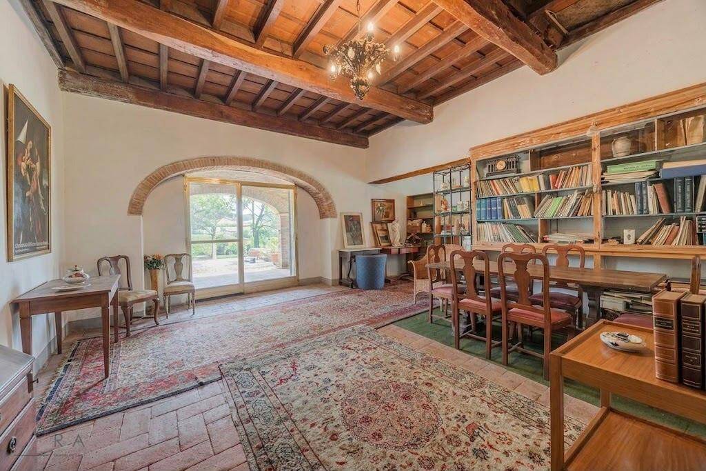 Geräumiges Wohnzimmer mit hohen Decken, Holzbalken und einer umfangreichen Bücherwand.