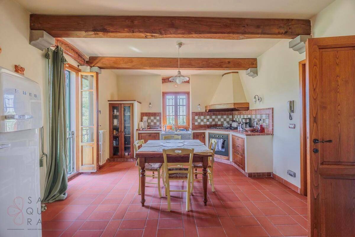 Traditionelle Küche mit Holztisch, Einbauschränken und sichtbaren Holzbalken an der Decke.