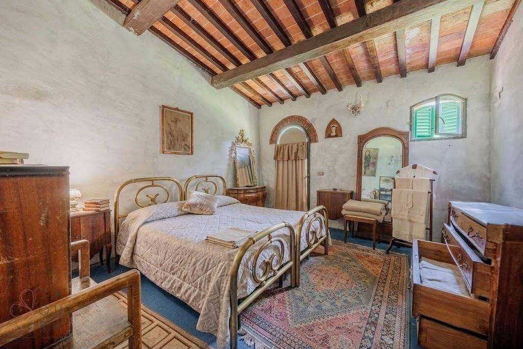 Charmantes Schlafzimmer mit schmiedeeisernem Bett, Holzbalkendecke und rustikalem Dekor.
