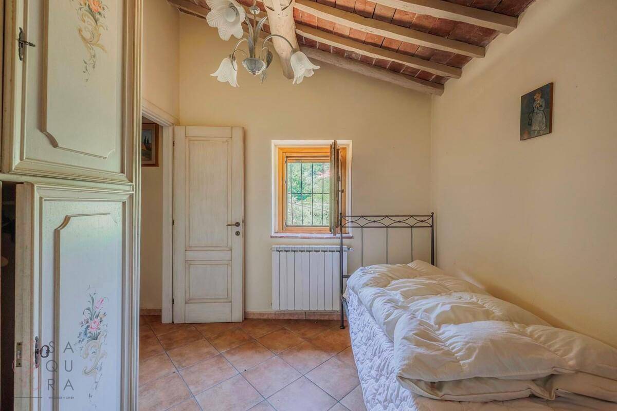 Schlafzimmer mit Einzelbett, Einbauschrank und rustikaler Holzbalkendecke unter dem Dach.