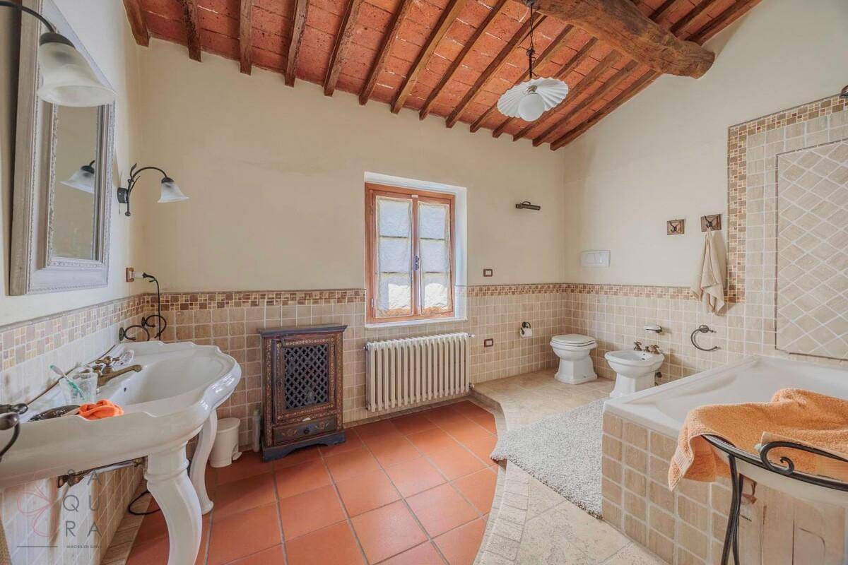 Geräumiges Badezimmer mit Badewanne, Bidet, zwei Waschbecken und Terrakottafliesen.