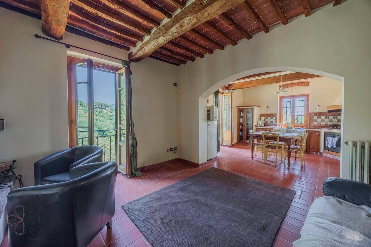 Gemütlicher Wohnbereich mit Terrakottaboden, Holzbalkendecke und Zugang zum französischen Balkon.