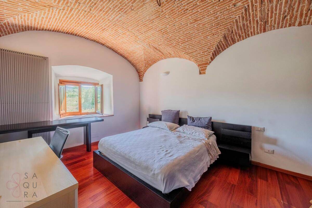 Geräumiges Schlafzimmer mit Holzboden, Schreibtisch und einer schönen Ziegelgewölbedecke.