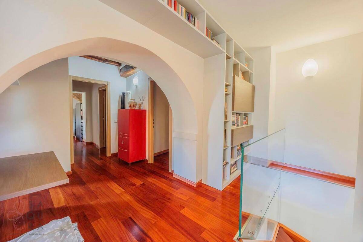 Heller Flur mit Holzboden, Bücherregalen und einem eleganten Bogendurchgang.