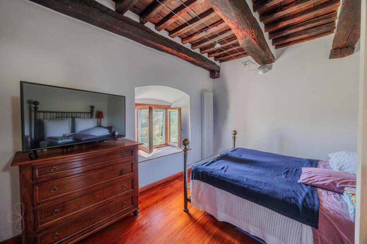 Gemütliches Schlafzimmer mit Holzboden, Holzbalkendecke und einem Fenster mit Ausblick.