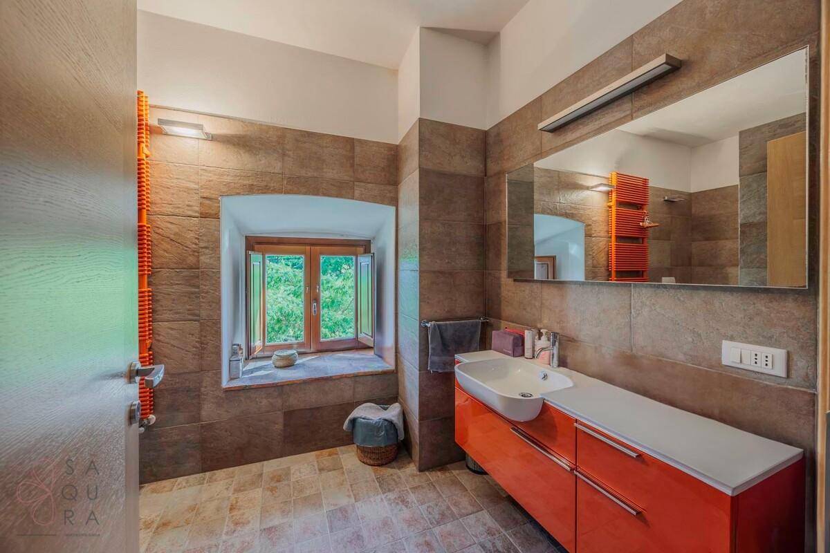 Helles Badezimmer mit orangefarbenem Waschtisch, Fenster und beheiztem Handtuchhalter.