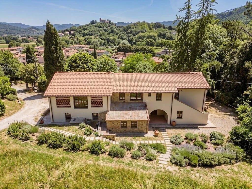 Luftaufnahme des Landhauses mit Ziegeldach und Blick auf die umliegende Landschaft und ein Dorf.