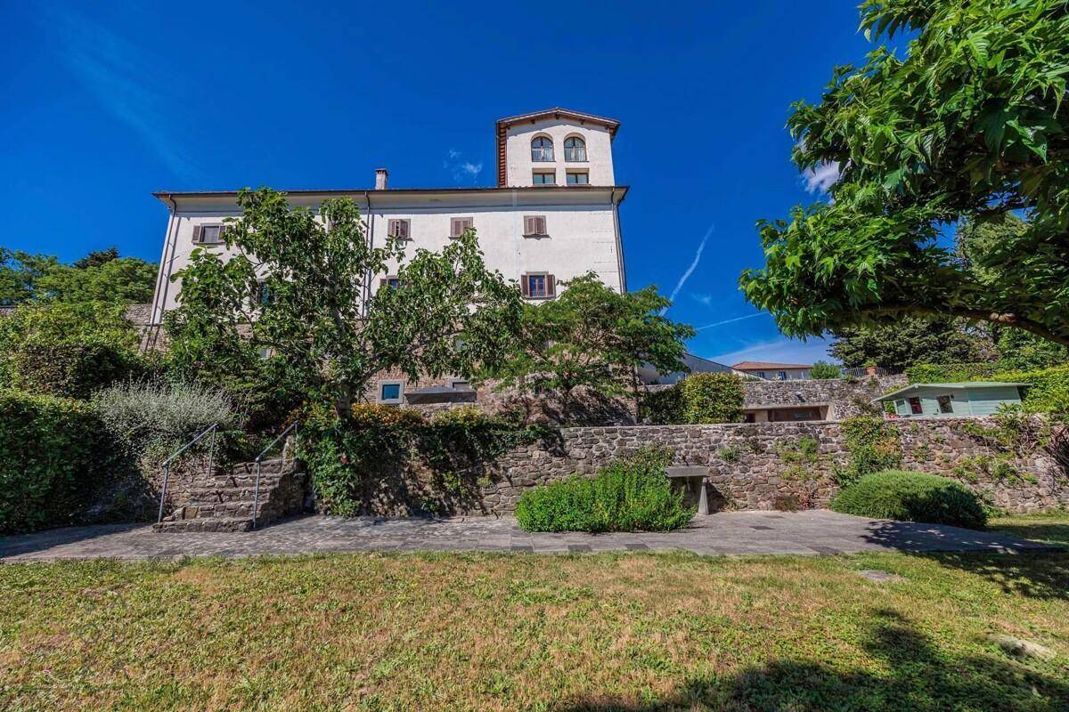 Historisches Gebäude mit Steinfassade, Garten und weitem Blick in die Landschaft.
