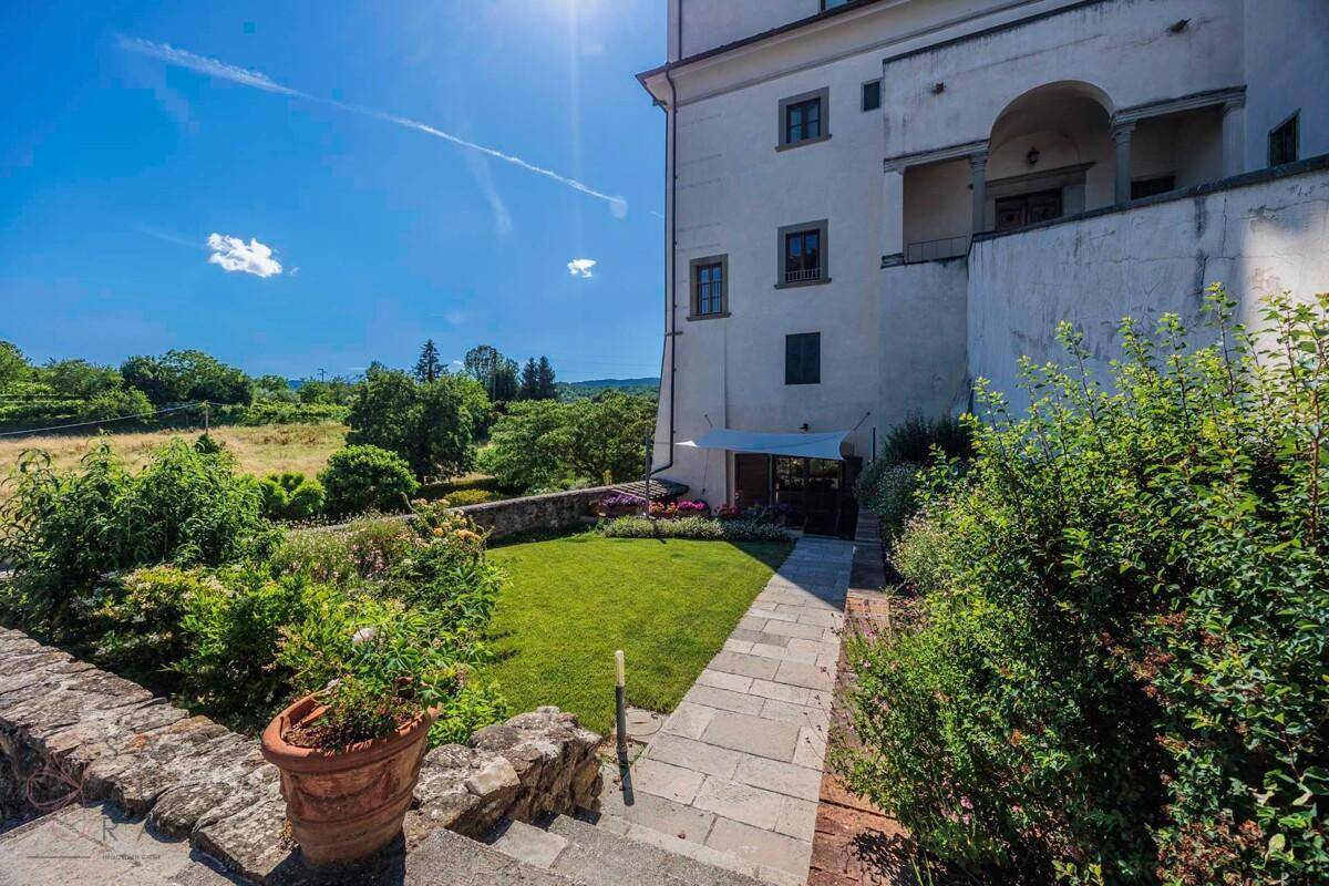 Gepflegter Gartenbereich mit Rasenfläche, Steinweg und üppiger Bepflanzung.