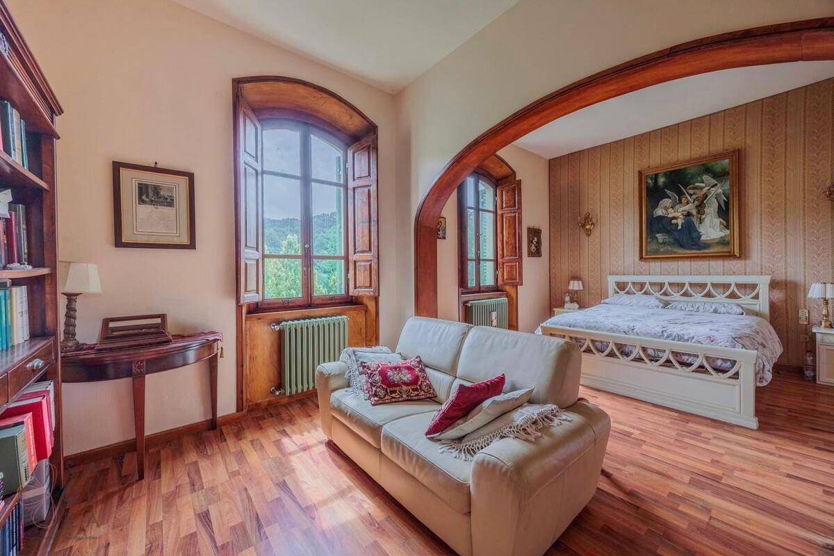 Großes Schlafzimmer mit Holzboden, einem bequemen Sofa und einem Doppelbett im traditionellen Stil.