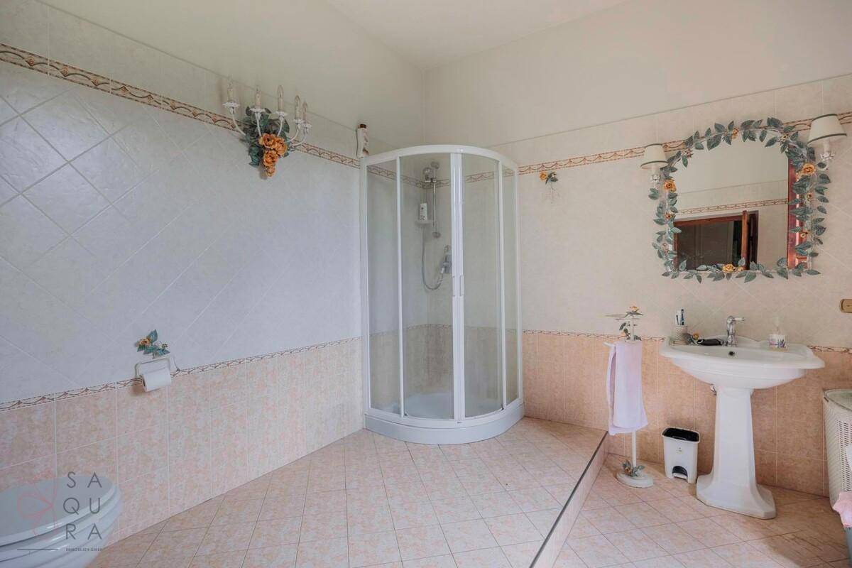 Geräumiges Badezimmer mit Duschkabine, Standwaschbecken und hellen Fliesen im traditionellen Stil.