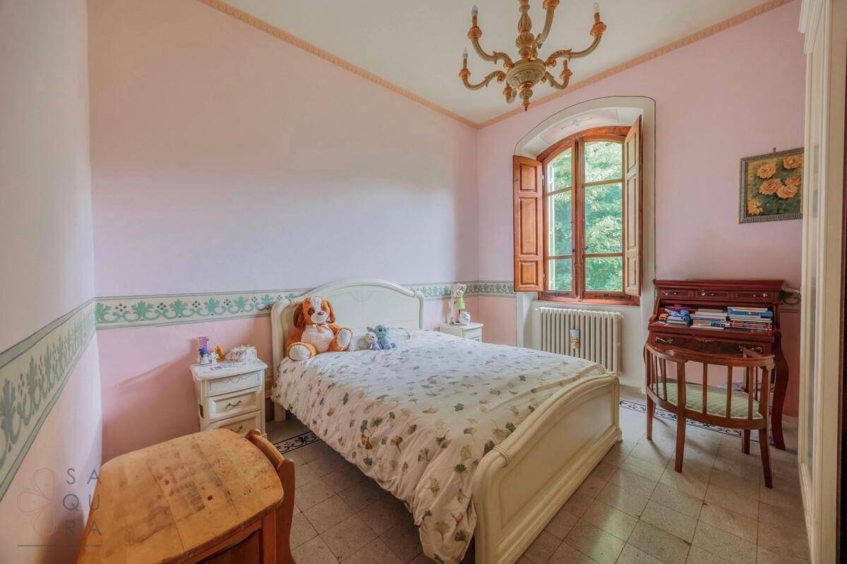Helles Schlafzimmer mit rosa Wänden, einem Doppelbett und einem Schreibtisch am Fenster.