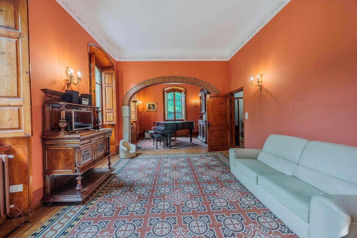 Geräumiges Wohnzimmer mit gemusterten Fliesen, einem weißen Sofa und einem Bogen zu einem weiteren Bereich.