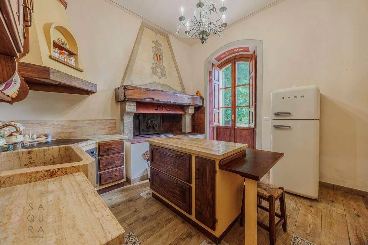 Rustikale Küche mit großem Kamin, Holzmöbeln und einem freistehenden Kühlschrank im Vintage-Stil.