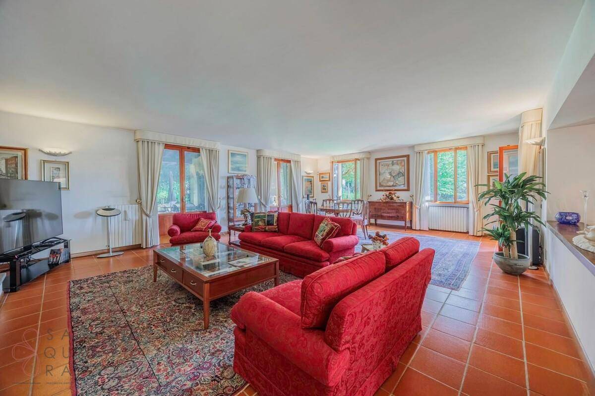 Komfortables Wohnzimmer mit roten Sofas, Terrakottafliesen und Blick in den Garten.