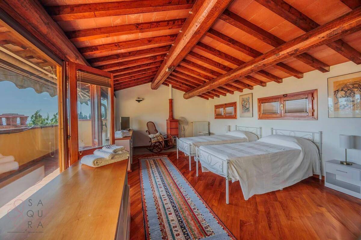 Gemütliches Schlafzimmer im Dachgeschoss mit Holzbalkendecke und Zugang zum Balkon.