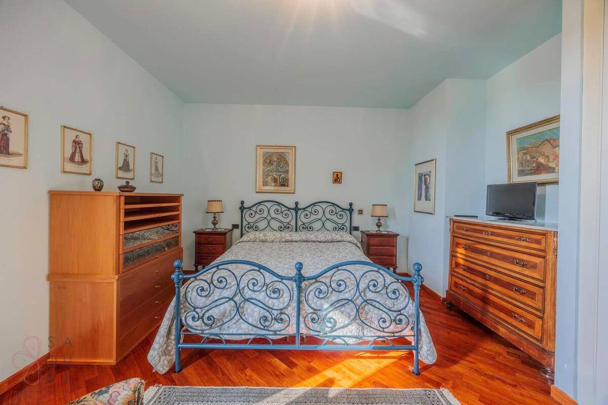 Helles Schlafzimmer mit Holzboden, blauem Metallbett und traditionellen Möbeln.