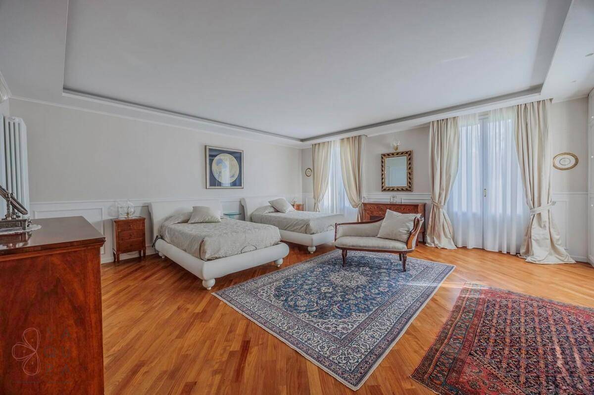 Elegantes Schlafzimmer mit Holzboden, zwei Einzelbetten und großen Fenstern.