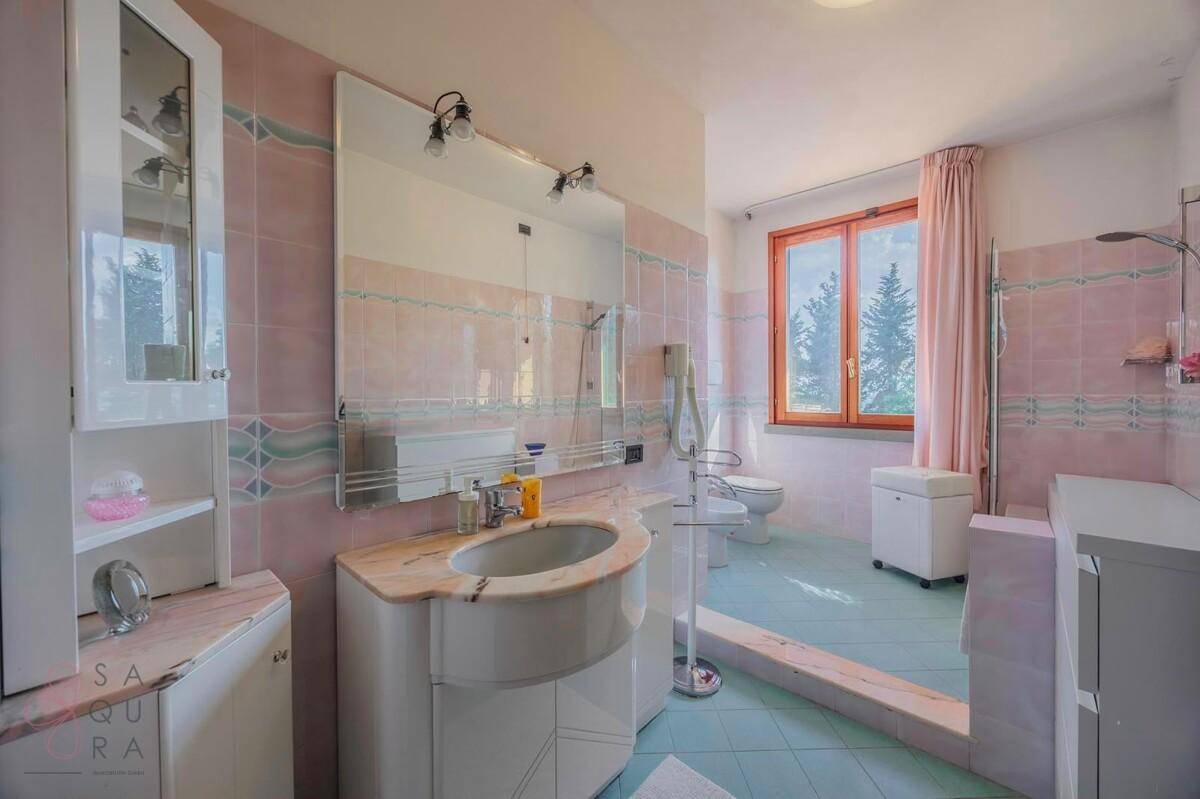 Badezimmer im 80er-Jahre-Stil mit rosa und blauen Fliesen, Dusche und Fenster.