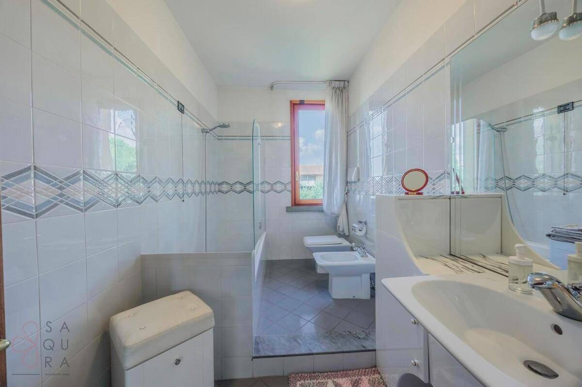 Helles Badezimmer mit weißen Fliesen, Dusche, WC und Bidet.
