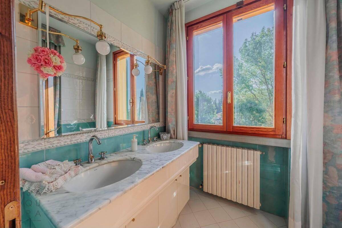Badezimmer mit Doppelwaschbecken, Marmorplatte und grünen Wandfliesen.