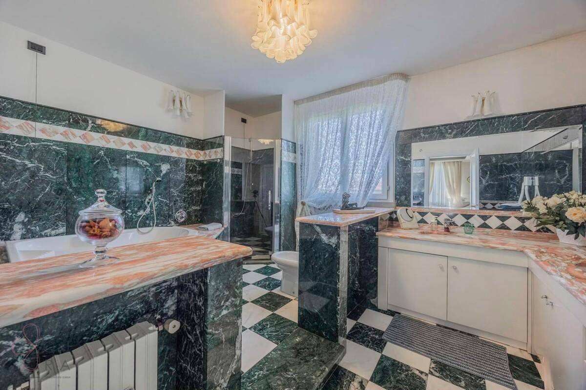 Luxuriöses Badezimmer mit grünem und rosa Marmor, Badewanne und separater Dusche.