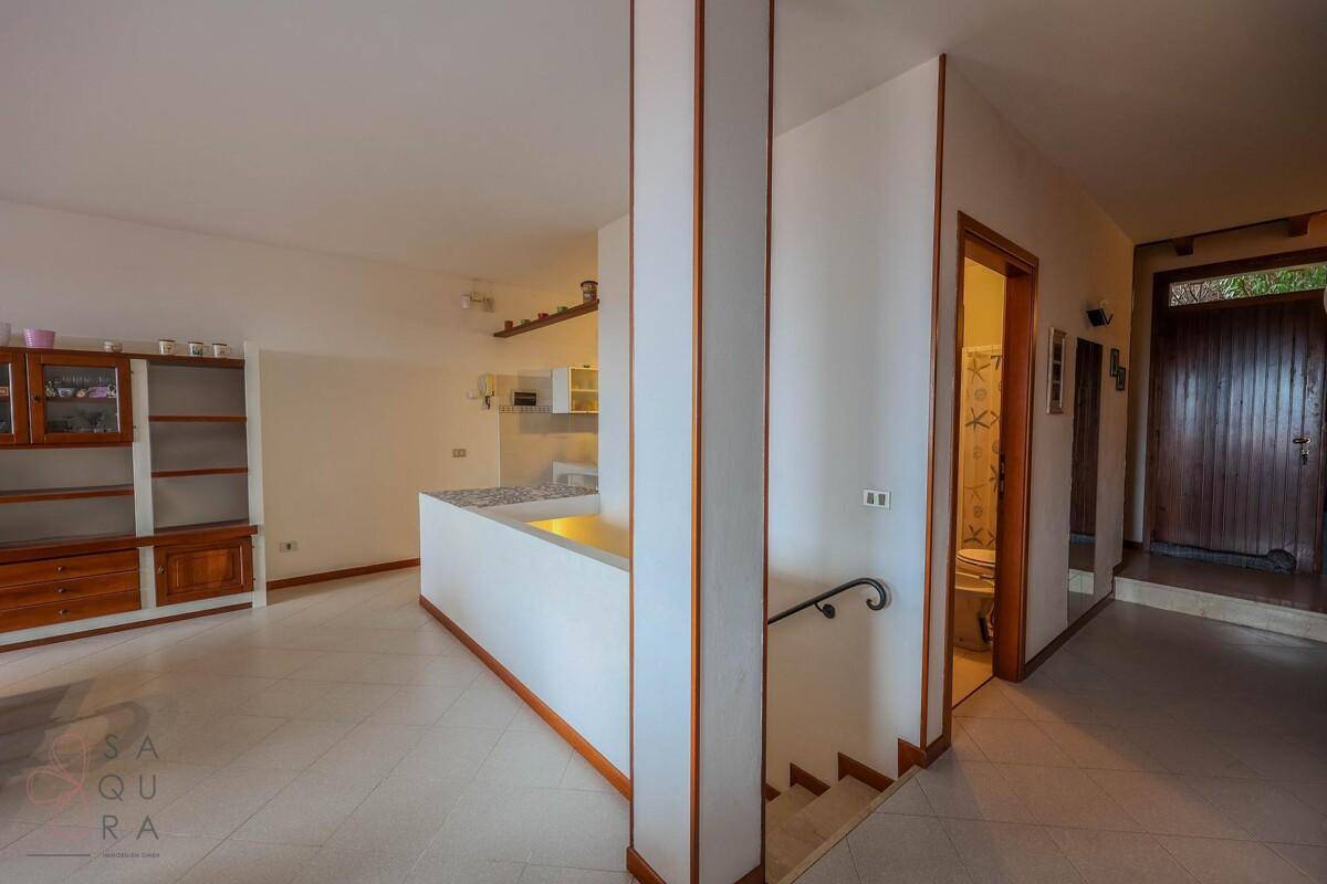 Eingangsbereich mit Treppe, der zur Küche und einem Badezimmer führt, mit Fliesenboden.