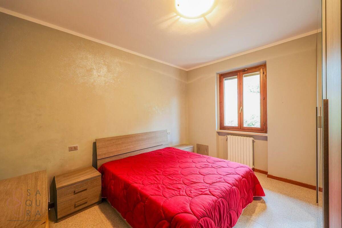 Helles Schlafzimmer mit Holzbett, Nachttischen und einem Fenster, das viel Tageslicht hereinlässt.